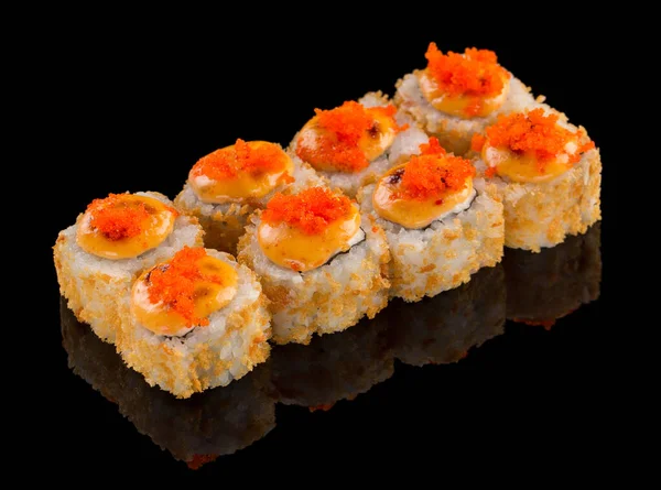 Жареные суши рулон Урамаки с соусом и икрой тобико сверху изолированы на черном фоне с отражением — стоковое фото