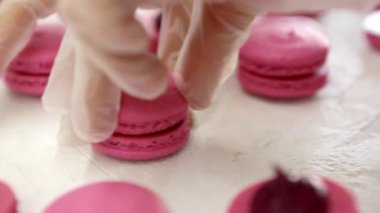 Pembe kurabiyeler yapıyorum. İki parça badem kurabiyesiyle dut kremasını birbirine bağlarken yakın çekim.