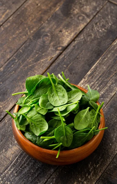 Fresh Spinach salad in Wooden Bowl on wooden table with Copyspace. — Stock Photo, Image