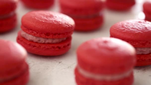 Detailní pohled na řadu červených makaronů na bílém pozadí. Klasický francouzský dezert. Ruka ti jednu vezme. — Stock video