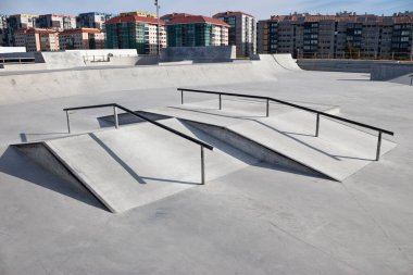 Boş bir beton kaykay parkında ezici numaralar için eğimli metal raylar