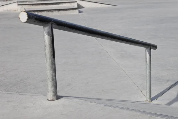 在空荡荡的混凝土溜冰场中用于磨削技巧的倾斜金属轨道 — 图库照片