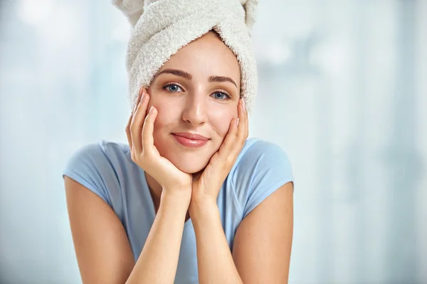 Een jonge brunette vrouw met een handdoek gewikkeld rond haar hoofd touch Rechtenvrije Stockfoto's