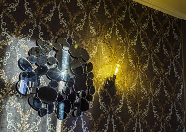 A beautiful mirror with an unusual design on the wall in the room, next to the lamp