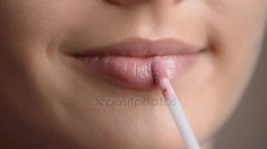 Makro görüntüleri genç kadının dudak parlatıcısı uygulayarak dudaklarında 
