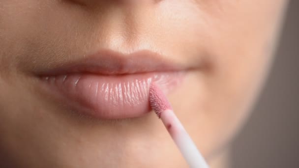 Lips in macro footage of young woman applying lip gloss — Stock Video