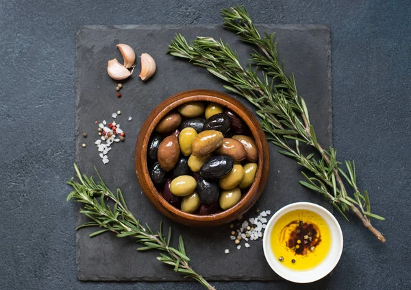Оливки и оливковое масло на темном камне — стоковое фото