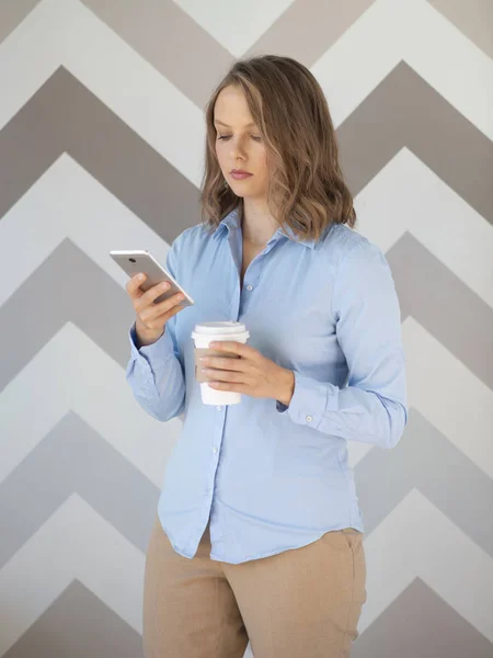 Businesswoman with coffee cup using mobile phone — Stockfoto