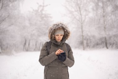 Kar yağışı sırasında cep telefonuyla mesajlaşan kadın
