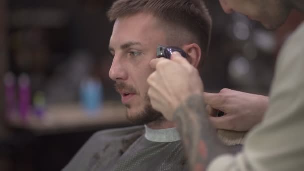 Fryzjer Pomocą Golarki Elektrycznej Zapewniając Fryzurę Dla Klienta Płci Męskiej — Wideo stockowe