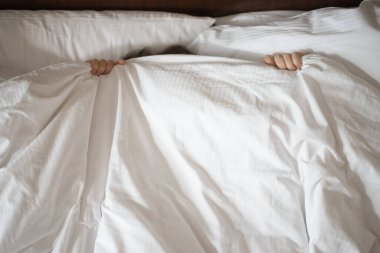 Kadın battaniyenin altında saklanıyor.