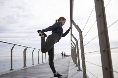 Kararlı bayan sporcunun yan görünüşü bacaklarını dışarı uzatarak antrenmana hazırlanıyor.
