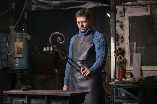 Blacksmith forging hot metal with hammer at anvil in blacksmith shop