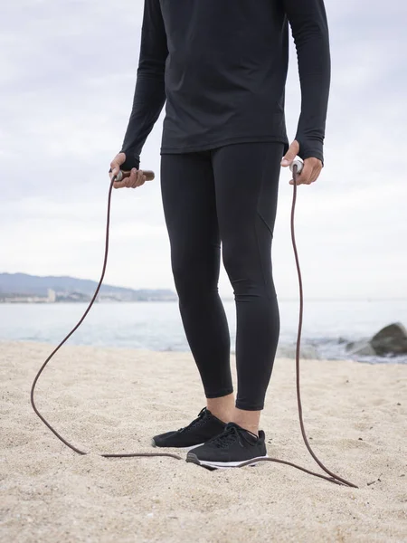 Handsome fit man with jumping rope standing at seaside. Man during workout outdoor