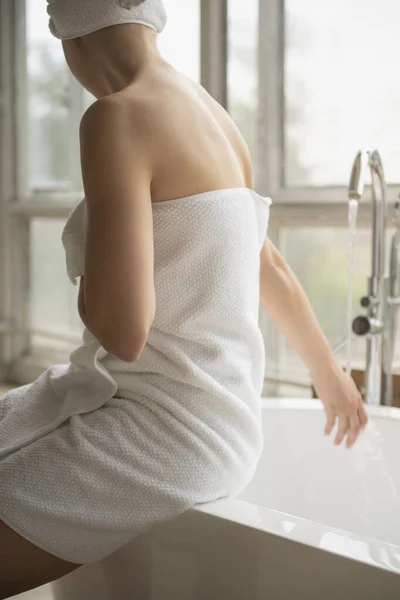 Mujer Envuelta Toalla Blanca Sentada Borde Bañera Tocando Agua Corriente — Foto de Stock