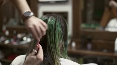 Berber uzun saçlı bir adam için saç kesimi yaparken tarak kullanıyor. 