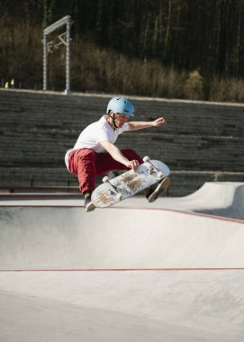 Genç adam kaykayla havada bir numara yapıyor.