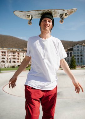 Kaykaylı neşeli genç adam kameraya bakıyor ve gülümsüyor.