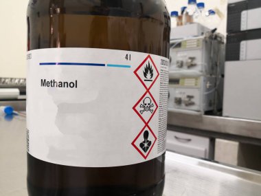Metanol, alkol ve zehirlilik, yanıcılık ve ölümle ilgili uyarılar içeren bir etiket içeren bir yıldırım koruması için kehribar cam şişe. Laboratuvarda kimyasal bir madde..