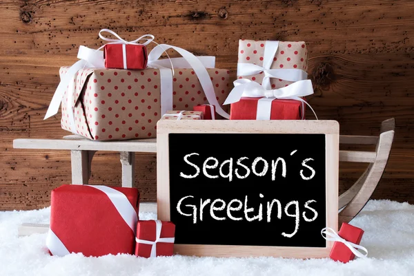 Slee met geschenken op sneeuw, tekst Seasons Greetings — Stockfoto