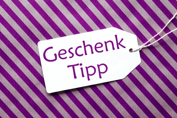 Метка на фиолетовой оберточной бумаге, Geschenk Tipp означает подарочный совет — стоковое фото