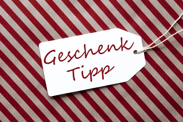 Étiquette sur papier d'emballage rouge, Geschenk Tipp signifie Conseil cadeau — Photo
