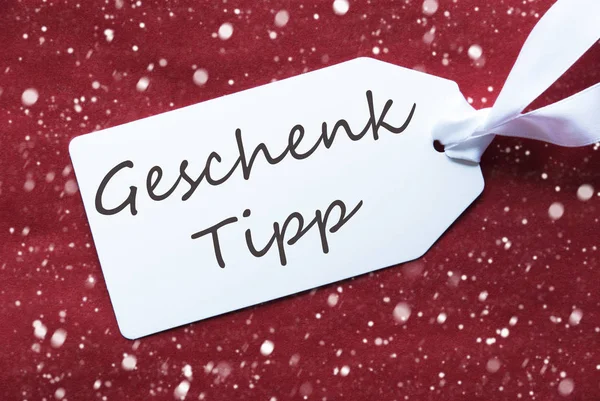 Étiquette sur fond rouge, flocons de neige, Geschenk Tipp signifie conseil cadeau — Photo
