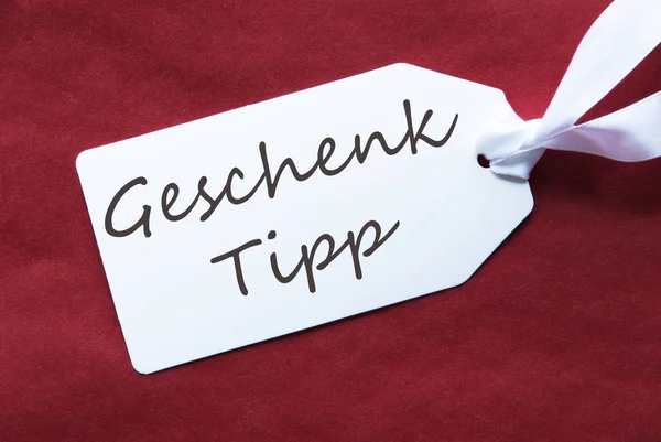 Une étiquette sur fond rouge, Geschenk Tipp signifie Conseil cadeau — Photo
