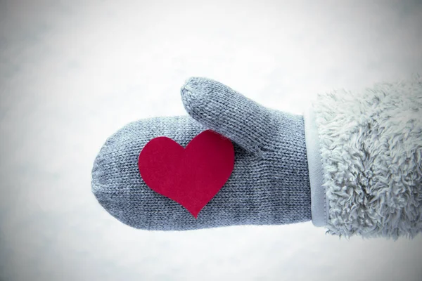 Шерстяная перчатка с красным сердцем, снежный фон — стоковое фото