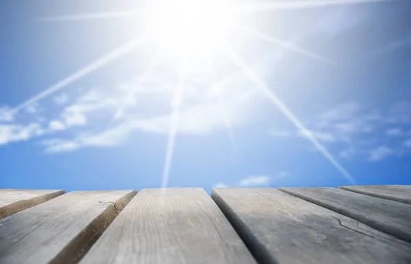 Arka plan olarak güneşli mavi gökyüzü ile ahşap tahta — Stok fotoğraf