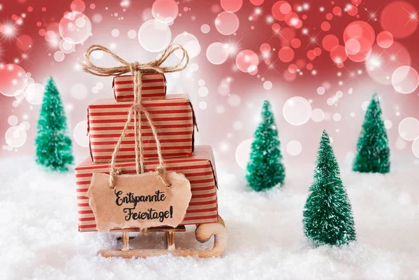 Sled, Presente, Neve, Entspannte Feiertage significa Buon Natale, sfondo rosso — Foto Stock