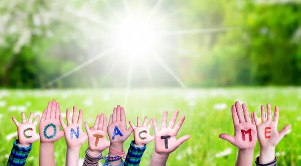 Mani dei bambini che costruiscono parola Contattaci, prato d'erba — Foto Stock