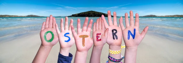 Children Hands Building Word Ostern Means Easter, Ocean Background — Stock Photo, Image