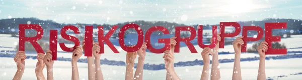 Pessoas mãos segurando palavra Risikogruppe significa grupo de alto risco, fundo de inverno — Fotografia de Stock