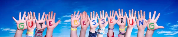 Enfants mains construire mot Gute Besserung signifie guérir bientôt, ciel bleu — Photo