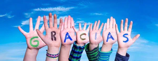 Viele Kinderhände bauen Wort Gracias bedeutet Danke, blauer Himmel — Stockfoto