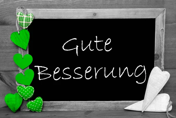 Balckboard con decoración verde del corazón, texto Gute Besserung significa recuperarse pronto — Foto de Stock