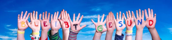 Dzieci Ręce trzymające słowo Bleibt Gesund oznacza Bądź zdrowy, Niebieskie Niebo — Zdjęcie stockowe