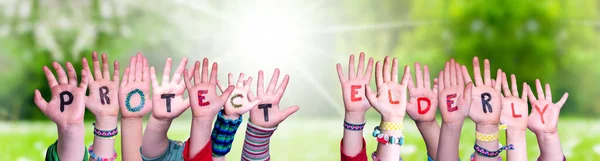 Le mani dei bambini che tengono parola proteggono anziani, prato d'erba — Foto Stock