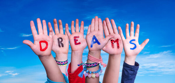 Children Hands Building Colorful English Word Dreams. Blue Sky As Background