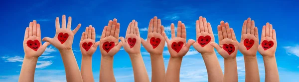 Mãos das crianças com símbolo do coração e sorrisos, fundo azul do céu — Fotografia de Stock