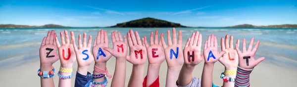子供の手が単語Zusammenhortを保持することは一緒に、海の背景を意味します — ストック写真