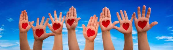 Mâinile copiilor cu simbolul inimii, fundal albastru al cerului — Fotografie, imagine de stoc
