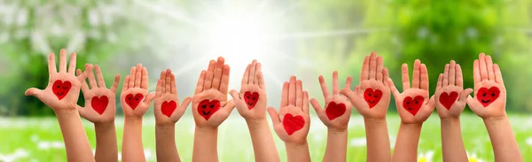 Copii mâini cu simbolul inimii și zâmbete, iarbă luncă ca fundal — Fotografie, imagine de stoc