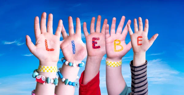 Manos de niños construyendo la palabra Liebe significa amor, cielo azul —  Fotos de Stock