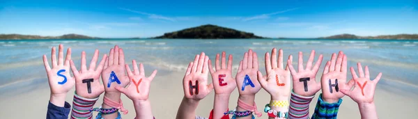 Dzieci Ręce trzymając słowo Bądź zdrowy, tło oceanu — Zdjęcie stockowe