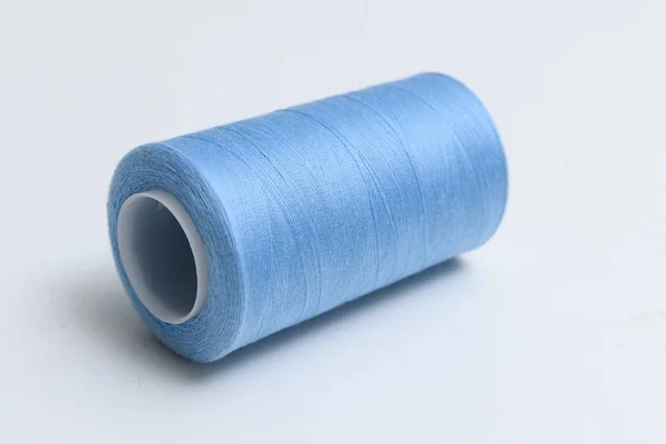 Carrete de hilos azules sintéticos o de algodón sobre fondo blanco. Carrete de hilo utilizado para tejer en la fabricación textil —  Fotos de Stock