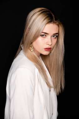 Sarı saçlı ve siyah elbiseli güzel genç mankenin yakın portresi, koyu arkaplanda fotostudio pozu.