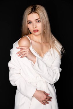 Sarı saçlı ve siyah elbiseli güzel genç mankenin yakın portresi, koyu arkaplanda fotostudio pozu.