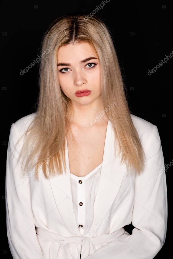 close up portrait of beautiful young model with blonde hair and black clothes, posing in photostudio on dark background